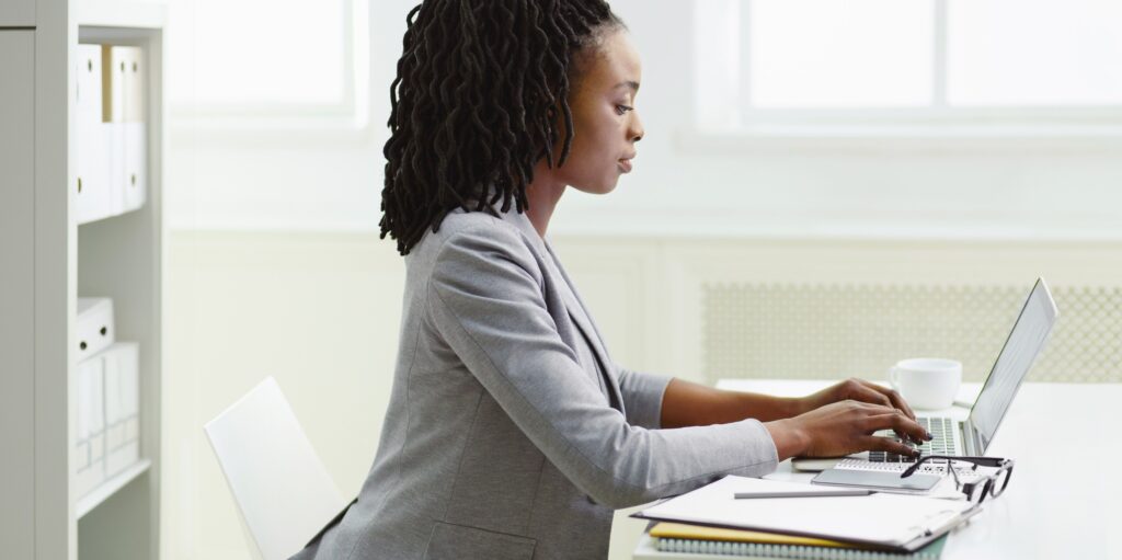 Confident woman typing on laptop in office